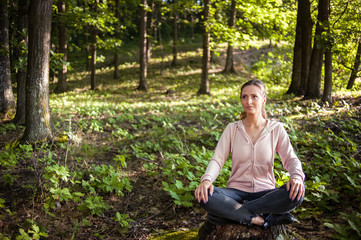 Naklejka na ściany i meble Beautiful woman meditating in the forest on a sunny morning