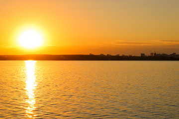 Bright sunset over the lake. Ripples on the water. The sky is orange
