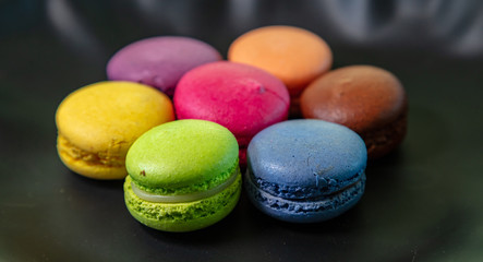 Colorful macarons on black background, close up view