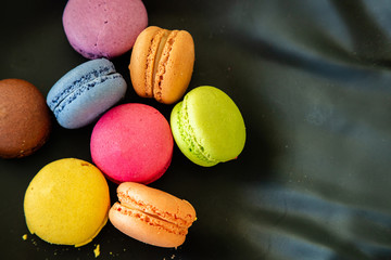 Colorful macarons on black background, close up view