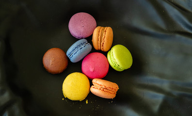 Colorful macarons on black background, close up view