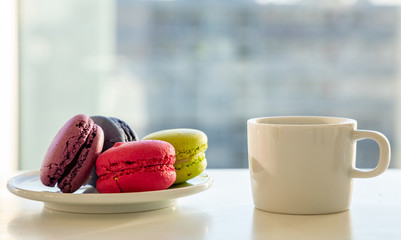 Colorful macarons and coffee cup on white background, close up view