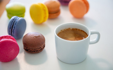 Colorful macarons and coffee cup on white background, close up view
