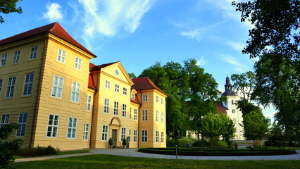 Fototapeta na wymiar Panoramaansicht von Schloss Mirow in der Abendsonne mit Stadtkirche und grünen Bäumen
