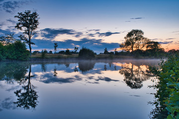 evening view of the water with trees and clouds reflected in the water