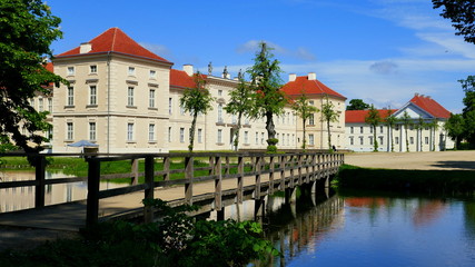 Fototapeta na wymiar romantische Holzbrücke führt über Wasser zum Vordereingang von Schloss Rheinsberg in Brandenburg