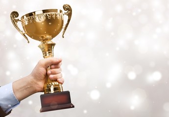 Hand holding golden trophy on blurred background