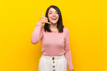 Young Mexican woman over isolated yellow background making phone gesture. Call me back sign