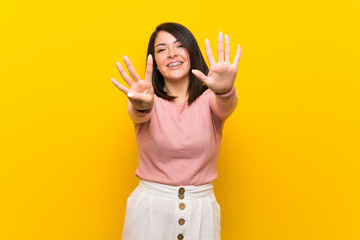 Young Mexican woman over isolated yellow background counting nine with fingers