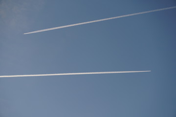 estelas blancas de aviones en sentido opuesto sobre cielo azul
