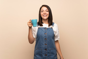 Young Mexican woman over isolated background holding hot cup of coffee