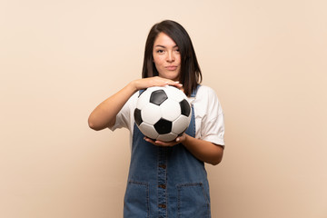 Young Mexican woman over isolated background holding a soccer ball