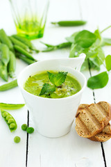 Green pea soup with croutons on wooden rustic background