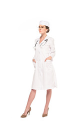 full length view of young doctor in white coat with stethoscope posing with hands in pockets isolated on white