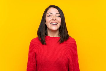Young Mexican woman with red sweater over yellow wall with surprise facial expression