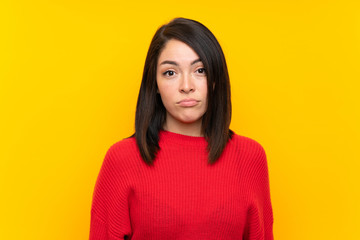 Fototapeta premium Young Mexican woman with red sweater over yellow wall sad