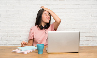 Young Mexican woman with a laptop having doubts with confuse face expression