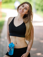 Young sporty woman with fitness beverage bottle