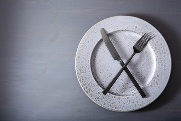 Fototapeta na wymiar concept of intermittent fasting and ketogenic diet, weight loss. fork and knife crossed on a plate
