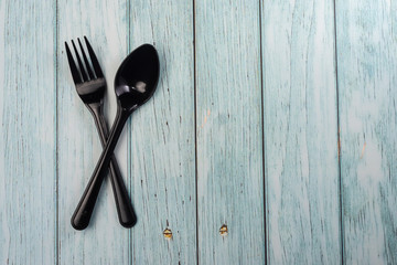 Plastic Spoon and Fork on wooden background. Negative space
