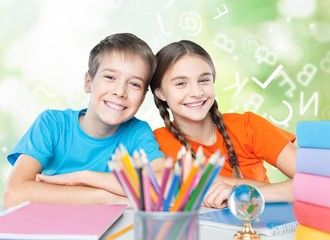 Happy children sitting by the table during lesson