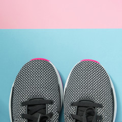 Woman Sneakers lie on a multi-colored pastel pink and blue surface. Top view.