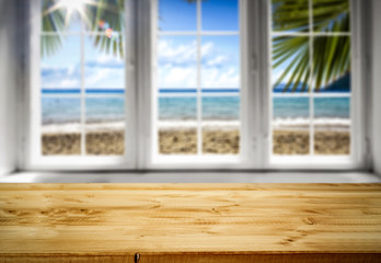 Table top background and white window and the beautiful sunny ocean beach view. Empty space on the table top for an advertising product.