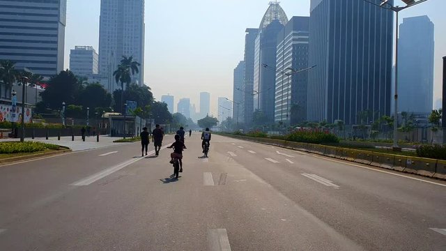 JAKARTA, Indonesia - July 03, 2019: Back view of little girl riding bicycle on the empty street during car free day event on the weekend morning in Jakarta city. Shot in 4k resolution