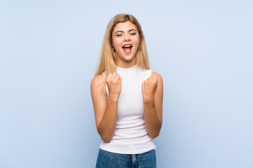 Teenager girl over isolated blue background surprised and pointing finger to the side