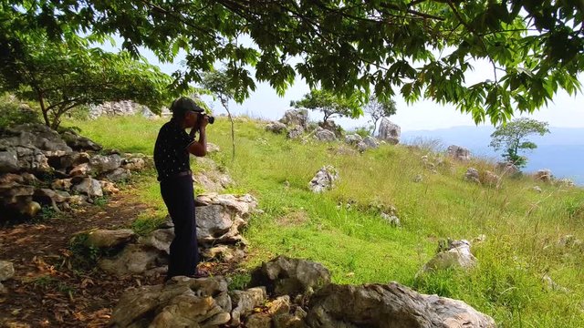 Senior man taking nature picture with a digital camera on the hill. Shot in 4k resolution