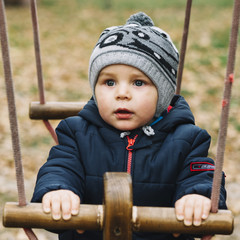 Toddler boy in warm clothes on seesaw