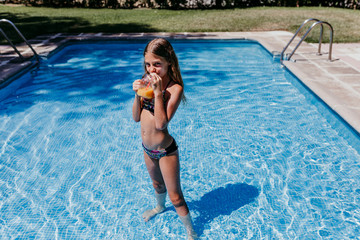 beautiful teenager girl at the pool drinking healthy orange juice and having fun outdoors....