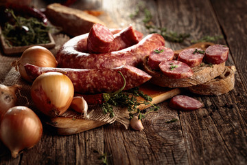 Dry-cured sausage with bread and spices on a old wooden table.