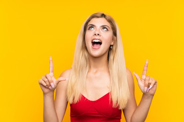 Teenager girl over isolated yellow background pointing with the index finger a great idea