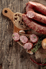 Dry-cured sausage with bread and spices on a old wooden table.