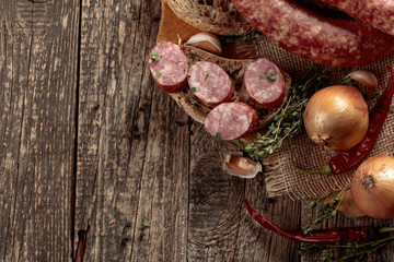 Dry-cured sausage with bread and spices on a old wooden table.