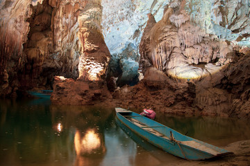 Fototapeta na wymiar Old blue boat parked inside Phong Nha Cave at Phong Nha National Park in Vietnam. Underground part of the Son River among beautiful stalactites and stalagmites.