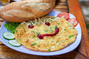 cheerful breakfast, omelette with a smile from ketchup, bread, vegetables and salad