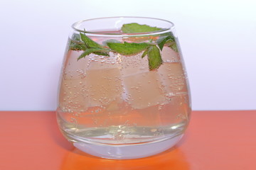 Refreshing drink with gas bubbles. Nalit in a transparent glass. It laid crushed ice. Decorated with mint leaves.
