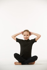 Fototapeta premium A school-age girl in black clothes stands on a white clean background.