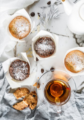 Cupcakes or muffins with cookies and cup of tea on light marble background with napkin. Holiday cake celebration, delicious dessert, top view