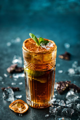 Fresh cocktail with cola, lime, chocolate and ice in glass on dark blue background. Summer cold drink and cocktail, selective focus