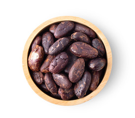 Group of roasted unpeeled cocoa beans in wood bowl isolated on white background. top view