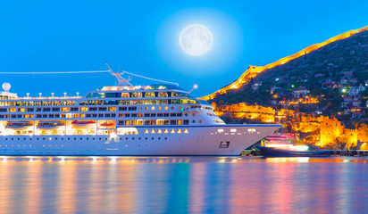 Beautiful white giant luxury cruise ship on stay at Alanya harbor with full moon 