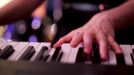 Musician girl playing the synthesizer during the concert. The fingers of the girl press the keys of the synthesizer. Shooting close-up.