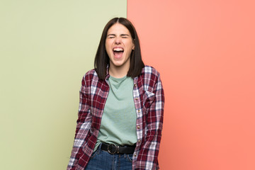 Young woman over isolated colorful wall shouting to the front with mouth wide open