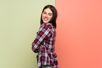Obraz premium Young woman over isolated colorful wall with arms crossed and happy