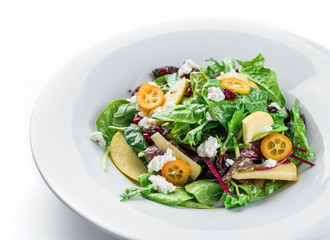 Healthy fresh salad with mix greens, apple, cream cheese, cranberry, sauce and edible flowers in plate on isolated white background. Healthy food, vegetarian dieting, close up