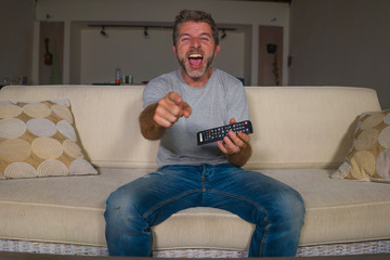 home lifestyle portrait of young happy and attractive man watching television comic show or comedy...