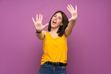 Young woman over isolated purple wall counting ten with fingers